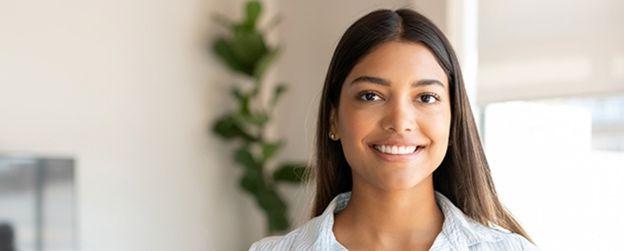 A person in an office setting smiles at the camera 